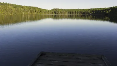 Ruhige Seelandschaft mit Holzsteg im Vordergrund.