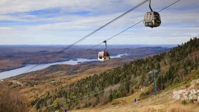 Eine Seilbahn fährt über eine herbstliche Berglandschaft mit See.