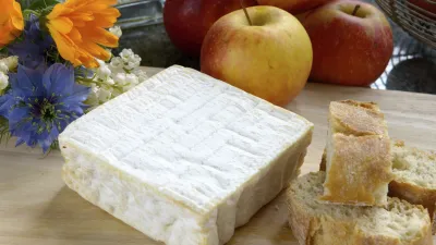 Französischer Weichkäse mit Äpfeln und Brot auf Holzbrett