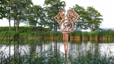 Holzskulptur im Fluss, umgeben von Schilf und Bäumen