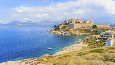 Korsische Küstenlandschaft mit mittelalterlicher Zitadelle und blauem Meer.