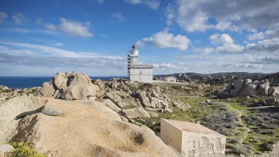 Sardinischer Leuchtturm thront auf felsiger Küstenlandschaft.