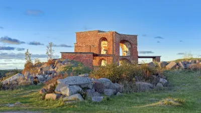 Historischer Wachturm aus Stein steht auf einer grasbewachsenen Klippe.
