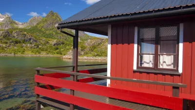 Rotes Holzhaus am Fjord mit Blick auf die Berge