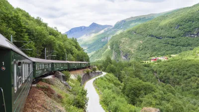 Grüner Zug fährt entlang einer kurvigen Bergstrecke in Norwegen.