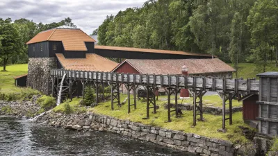Historische Fabrik mit rotem Dach und Holzsteg am Wasser