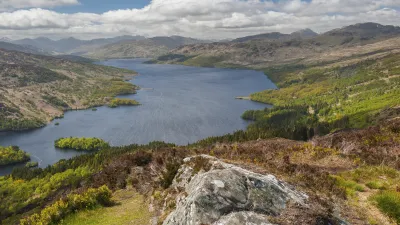 Schottischer See mit grünen Hügeln und bewölktem Himmel