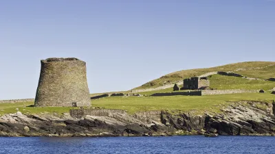 Der historische Mousa Broch Turm steht auf einer grünen Klippe über dem Meer.