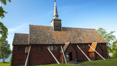 Historische norwegische Stabkirche Kvernes steht auf einer grünen Wiese.