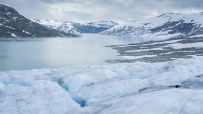 Gletschersee mit Eisformationen und schneebedeckten Bergen im Hintergrund