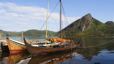 Wikingerschiffe liegen im Wasser vor einer Bergkulisse