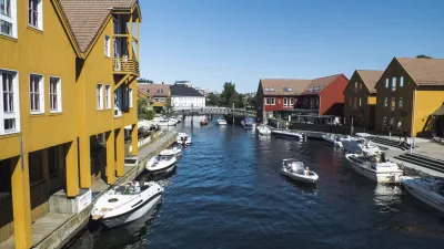 Boote fahren auf einem Kanal zwischen bunten Häusern in Kristiansand.