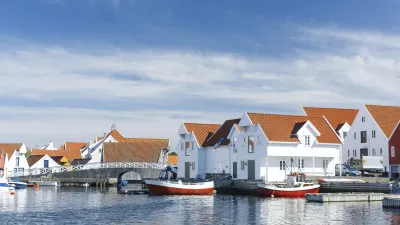Weiße Holzhäuser säumen den Hafen mit roten Booten in Norwegen.