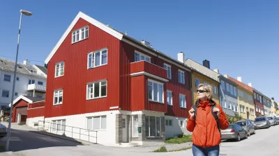 Eine Frau in roter Jacke geht an bunten Häusern vorbei