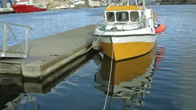 Gelbes Fischerboot liegt am Steg im Wasser.
