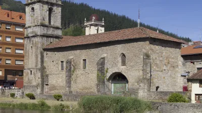 Historische Kirche mit Glockenturm am Flussufer in Balmaseda