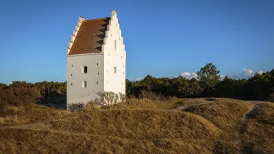 Weiße Kirche inmitten einer hügeligen Landschaft in Dänemark