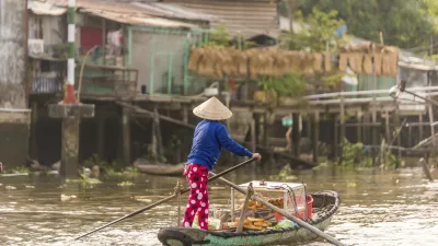 Ein Mann rudert mit einem kleinen Boot auf einem Fluss im Mekong-Delta.