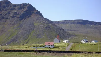 Eine kleine Kirche steht vor einer beeindruckenden Berglandschaft in Island.