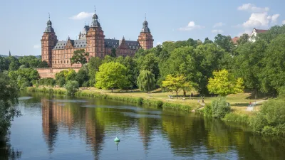 Schloss Johannisburg spiegelt sich im Main mit angrenzendem Park.