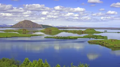 Grüner See mit kleinen Inseln vor vulkanischer Landschaft