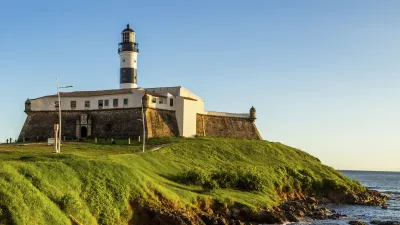 Historischer Leuchtturm steht auf einer grünen Klippe am Meer