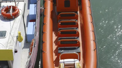 Oranges Schlauchboot liegt im Wasser an einem Steg.