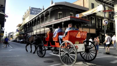Eine rote Pferdekutsche fährt auf einer belebten Strasse durch New Orleans.