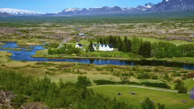 Historische Kirche in der isländischen Landschaft mit grünen Wiesen und Bergen.