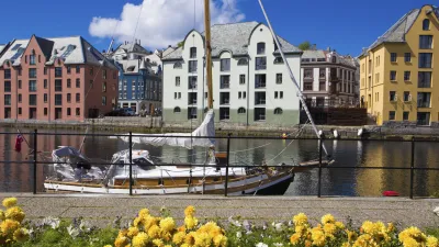 Ein Segelboot liegt vor farbenfrohen Häusern in einem norwegischen Kanal.