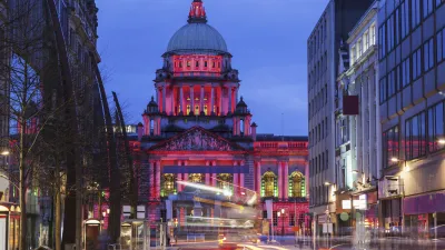 Beleuchtetes Rathaus von Belfast bei Nacht mit fließendem Verkehr.
