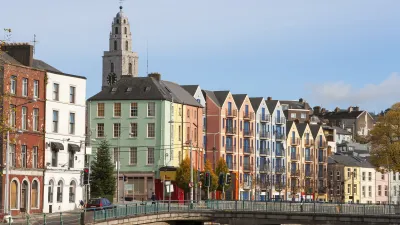 Bunte Häuser und eine Kirche säumen eine Brücke in Cork, Irland.