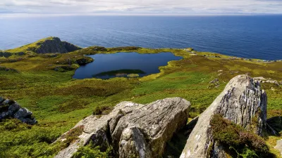 Grüner See in der irischen Landschaft mit Blick auf das Meer.