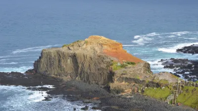 Felsige Küstenklippe mit grüner Vegetation am Meer