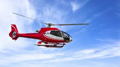 Roter Hubschrauber fliegt am blauen Himmel