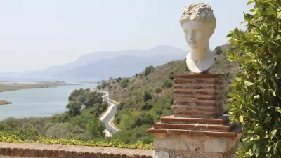 Ein weißer Skulpturenkopf thront auf einer Säule mit Blick auf die Landschaft.