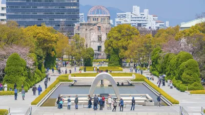 Friedensdenkmal in Hiroshima mit Besuchern und blühenden Bäumen