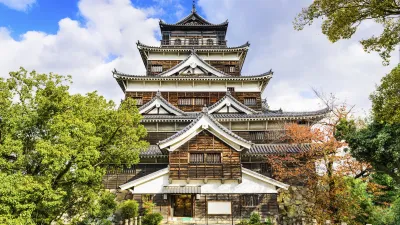 Historische japanische Burg mit dunkler Holzfassade und mehreren Etagen.