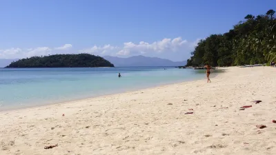 Strandlandschaft mit einer Person beim Spaziergang am weißen Sandstrand