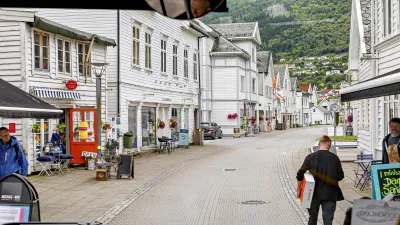 Eine belebte Straße mit traditionellen weißen Häusern in einer norwegischen Stadt.
