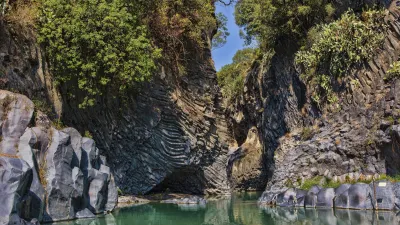 Grüner Fluss fließt durch eine Schlucht aus Basaltfelsen in Sizilien.