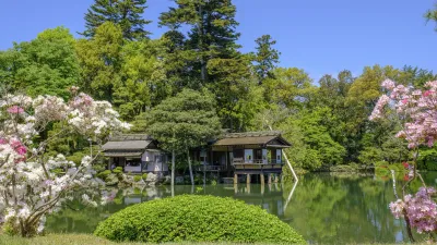 Traditionelles Teehaus spiegelt sich im ruhigen Teich im Kenrokuen Park.
