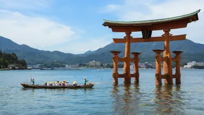 Rotes Torii-Tor im Wasser mit Boot und Bergen im Hintergrund