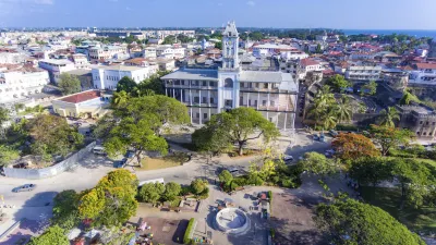 Historisches Gebäude in Stone Town, Sansibar, umgeben von üppiger Vegetation.