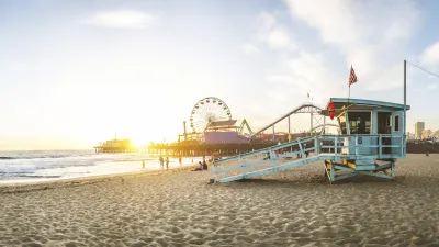 Sonnenuntergang über dem Santa Monica Pier mit Fahrgeschäften und Strand.