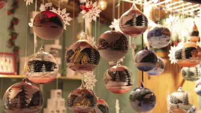 Dekorative Weihnachtskugeln mit Winterlandschaft hängen an Fäden.