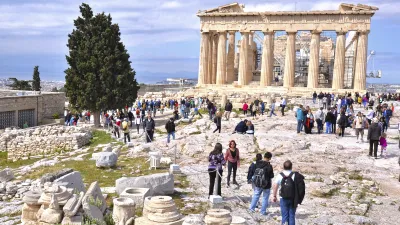 Besucher erkunden die Akropolis mit dem Parthenon im Hintergrund