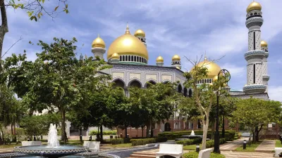 Prächtige Moschee mit goldenen Kuppeln und Minarett im grünen Park.