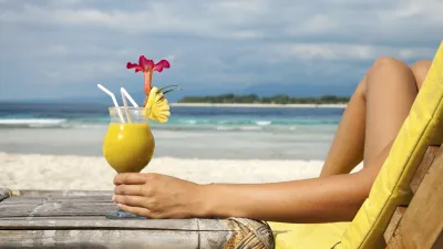 Cocktail und Füße am Strand genießen einen entspannten Urlaub.