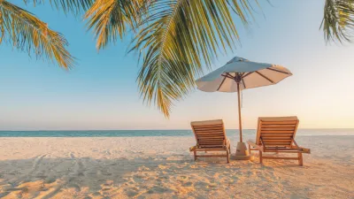 Zwei Liegestühle und ein Sonnenschirm stehen am tropischen Strand.